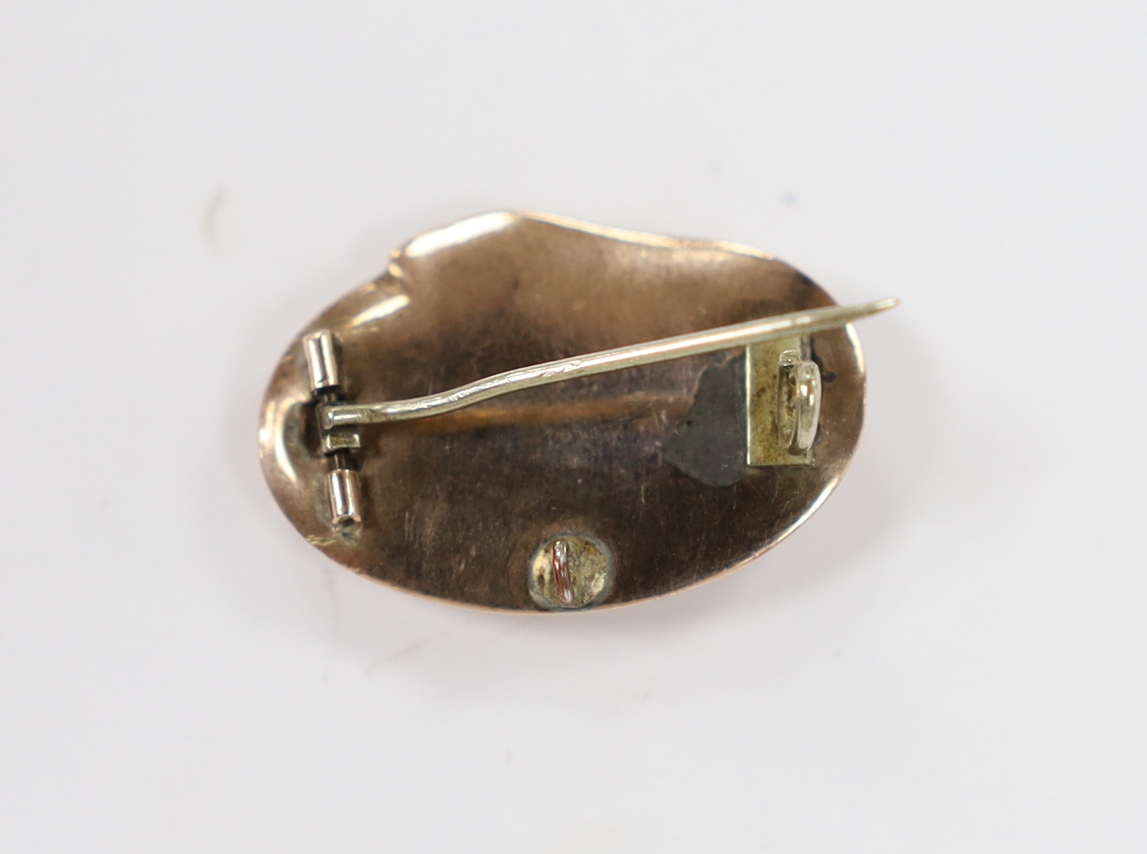 A Victorian yellow metal mounted oval mourning brooch, with plaited hair beneath a glazed panel and serpent border, 25mm.